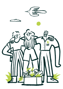 Tres personas abrazadas junto a una caja de verduras frescas.